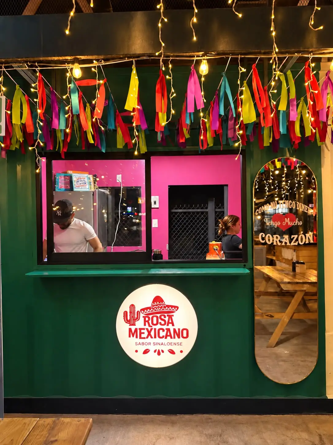 Contenedor verde de Rosa Mexicano con papel picado y su letrero rosa
